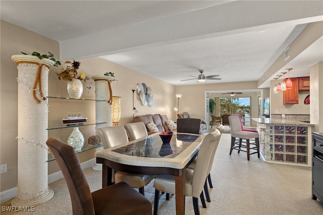 dining area featuring decorative columns, ceiling fan, and light colored carpet