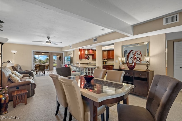 carpeted dining space featuring ceiling fan, beamed ceiling, and a textured ceiling