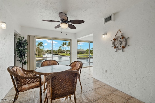 dining space with ceiling fan, light tile patterned floors, a water view, and a textured ceiling