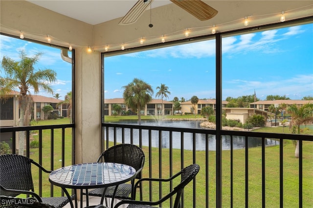 sunroom featuring ceiling fan, a water view, and track lighting