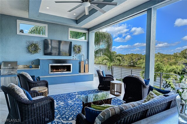 sunroom featuring ceiling fan, a raised ceiling, and exterior fireplace