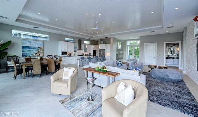 living room featuring ceiling fan, a raised ceiling, light tile patterned floors, and wooden ceiling