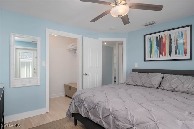 bedroom featuring a closet, light hardwood / wood-style floors, a spacious closet, and ceiling fan