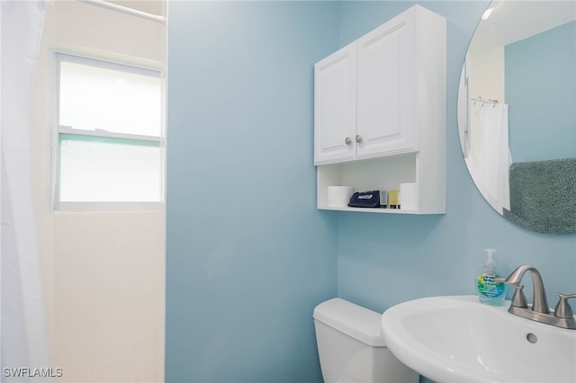 bathroom featuring curtained shower, sink, and toilet