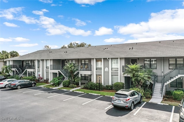 1208 Commonwealth Cir Unit J-103, Naples, FL 34116 - view of building exterior with stairs and uncovered parking