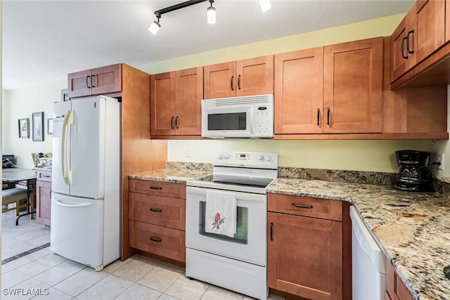 kitchen with light stone countertops, white appliances, light tile patterned floors, and track lighting