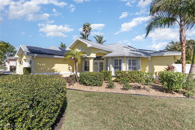 single story home with solar panels and a front yard