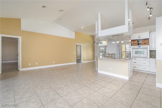 kitchen with white cabinets, oven, light tile patterned floors, and a kitchen island