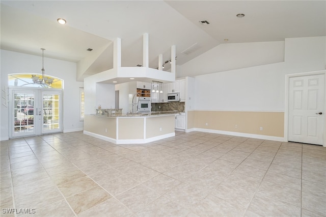 unfurnished living room with french doors, light tile patterned floors, high vaulted ceiling, and a notable chandelier