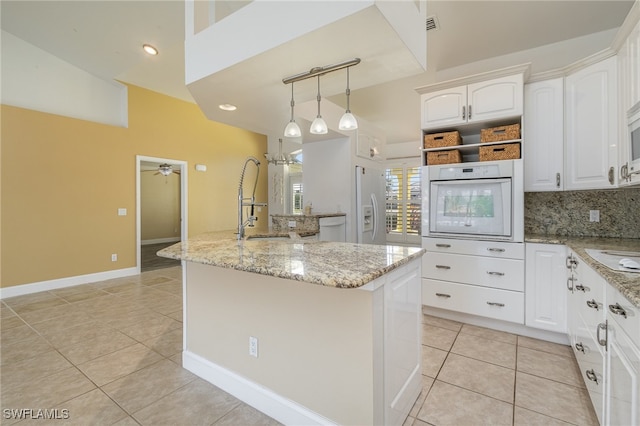 kitchen featuring ceiling fan, a kitchen island, vaulted ceiling, white appliances, and white cabinets