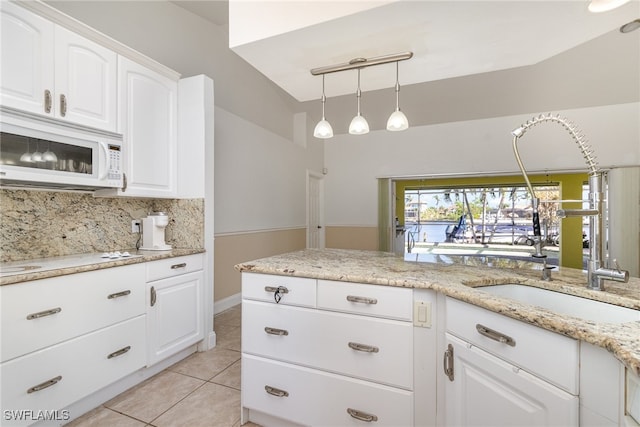 kitchen featuring white cabinetry, hanging light fixtures, vaulted ceiling, decorative backsplash, and light tile patterned flooring