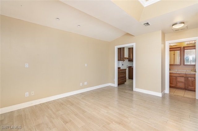 interior space featuring ensuite bathroom, vaulted ceiling, and light hardwood / wood-style floors