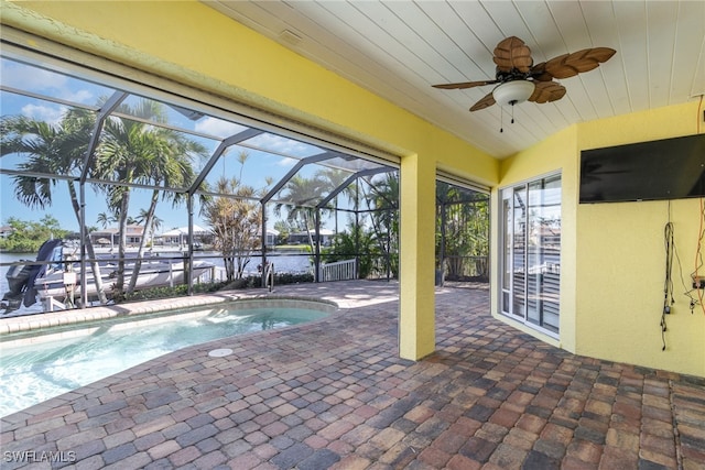 view of swimming pool with glass enclosure, ceiling fan, and a patio area