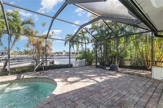 view of swimming pool featuring glass enclosure, a water view, and a patio