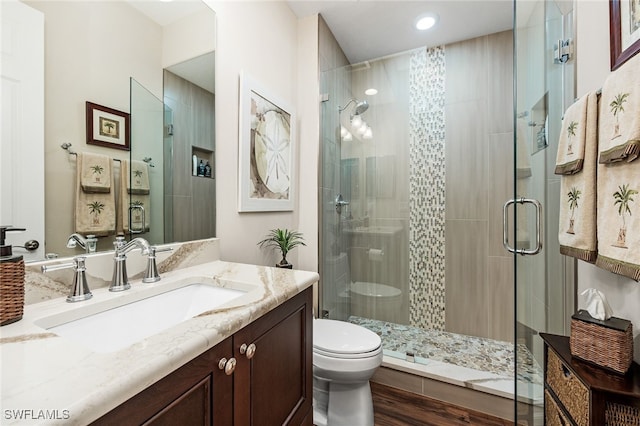 bathroom featuring vanity, wood finished floors, a shower stall, and toilet