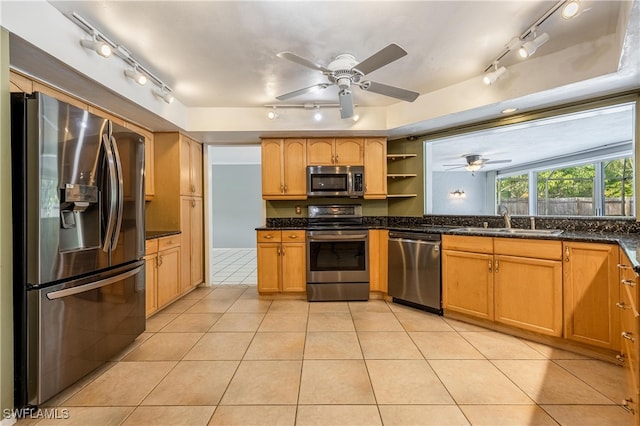 kitchen featuring sink, ceiling fan, dark stone countertops, light tile patterned floors, and appliances with stainless steel finishes