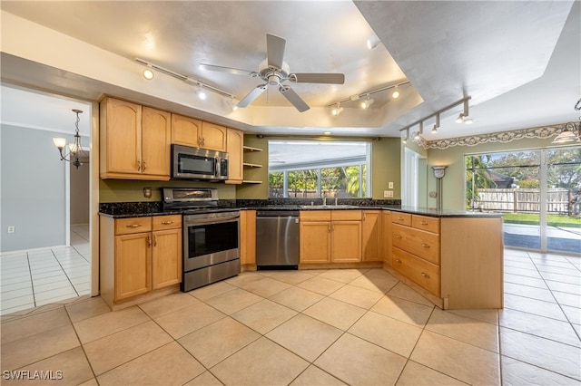 kitchen featuring appliances with stainless steel finishes, dark stone counters, sink, light tile patterned floors, and pendant lighting