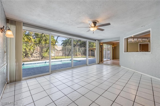 tiled empty room with a wealth of natural light, ceiling fan, and a textured ceiling