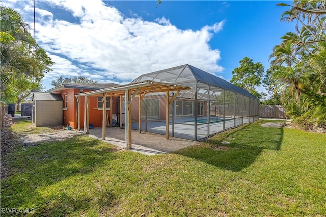 exterior space featuring a lawn, glass enclosure, a storage shed, and a patio