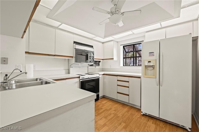 kitchen with white appliances, white cabinets, sink, ceiling fan, and light hardwood / wood-style flooring