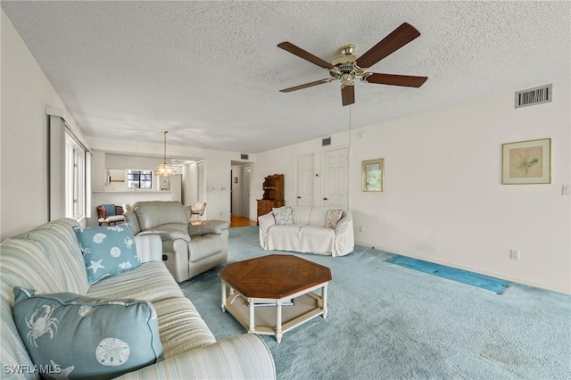 living room featuring carpet, ceiling fan with notable chandelier, and a textured ceiling