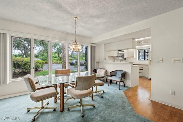 dining room featuring a textured ceiling, light hardwood / wood-style flooring, and a notable chandelier