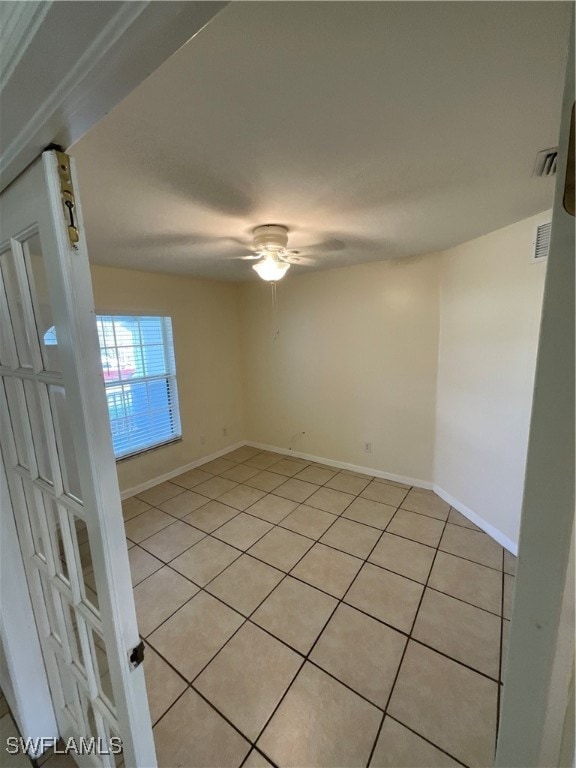 tiled spare room featuring ceiling fan