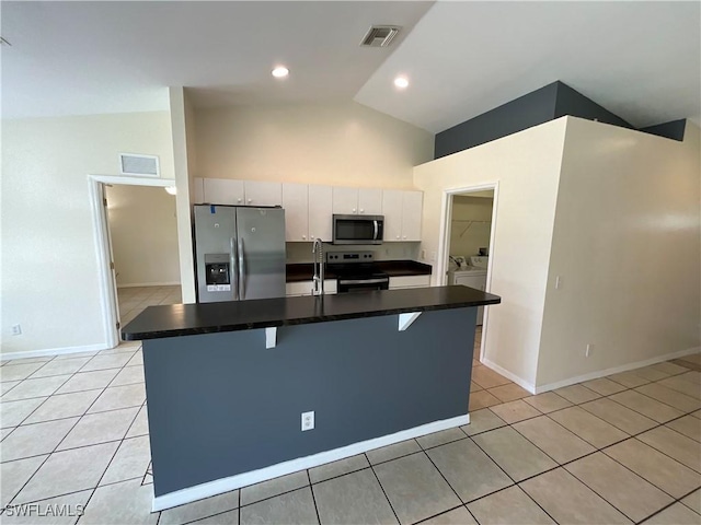 2917 43rd St W, Lehigh Acres, FL 33971 - kitchen featuring stainless steel appliances, washer and dryer, light tile patterned floors, dark countertops, and a kitchen breakfast bar