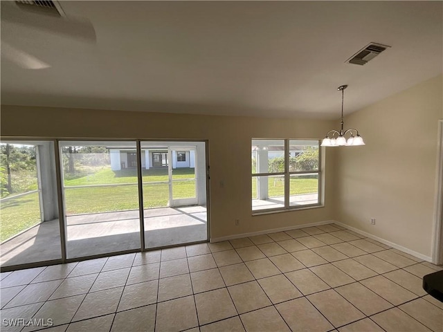 tiled empty room featuring a chandelier