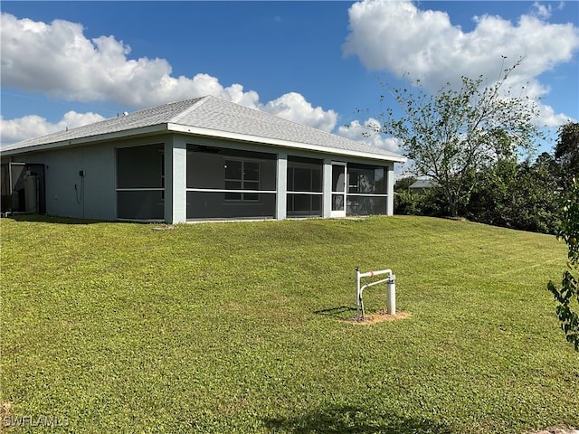 back of property with a sunroom and a lawn