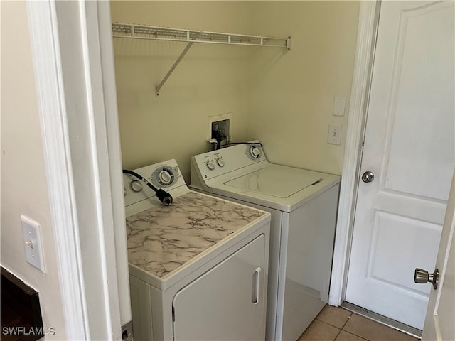 clothes washing area with washing machine and clothes dryer and light tile patterned floors