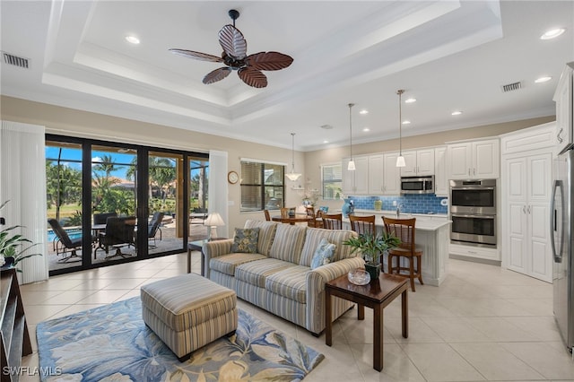 living room with a raised ceiling, crown molding, light tile patterned floors, and ceiling fan