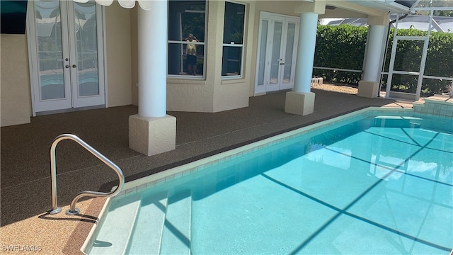 view of swimming pool with glass enclosure, a patio area, and french doors