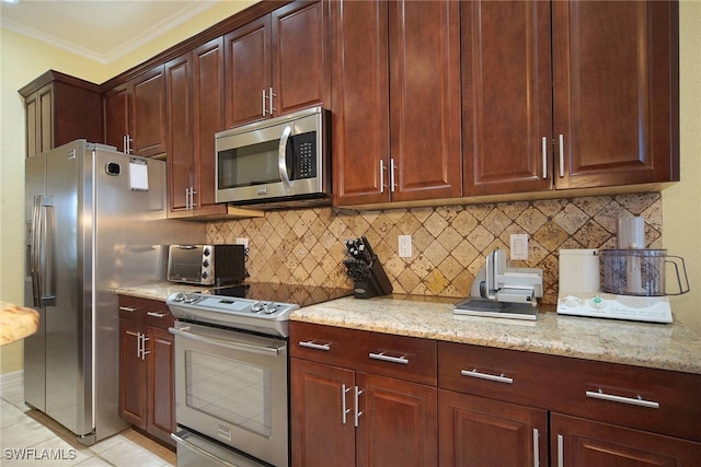 kitchen with decorative backsplash, light tile patterned floors, appliances with stainless steel finishes, crown molding, and light stone counters