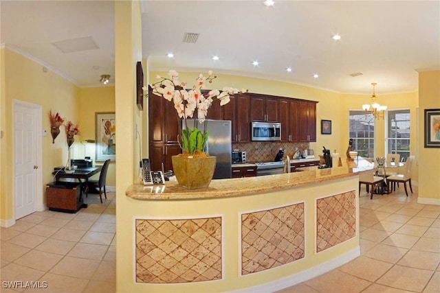 kitchen with light tile patterned flooring, pendant lighting, appliances with stainless steel finishes, crown molding, and backsplash