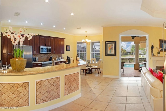 kitchen with tasteful backsplash, stainless steel appliances, light tile patterned floors, an inviting chandelier, and hanging light fixtures