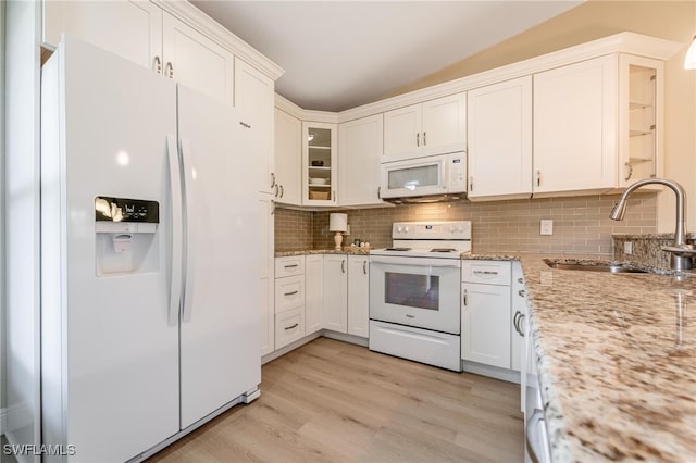 kitchen with lofted ceiling, white appliances, white cabinets, sink, and light wood-type flooring