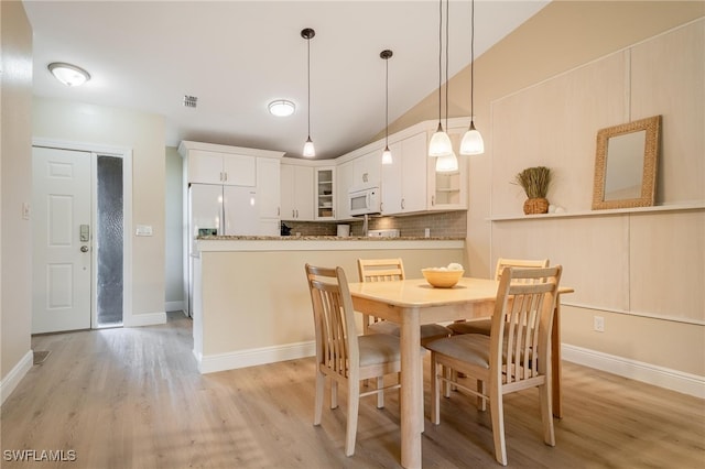 dining room with light wood-type flooring and lofted ceiling