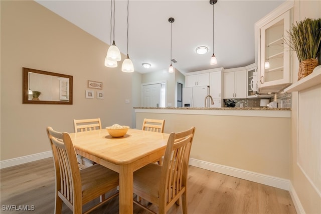 dining space featuring light hardwood / wood-style flooring and vaulted ceiling