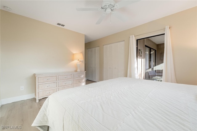 bedroom featuring two closets, light hardwood / wood-style flooring, and ceiling fan