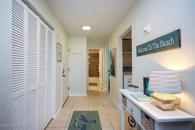 corridor with washer / dryer and light tile patterned flooring