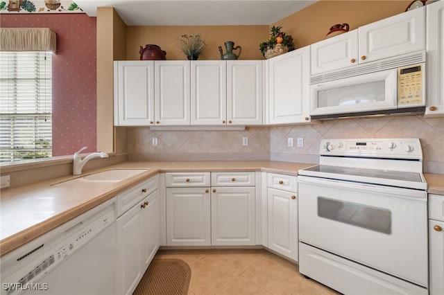 kitchen featuring white appliances, white cabinets, sink, light tile patterned floors, and tasteful backsplash