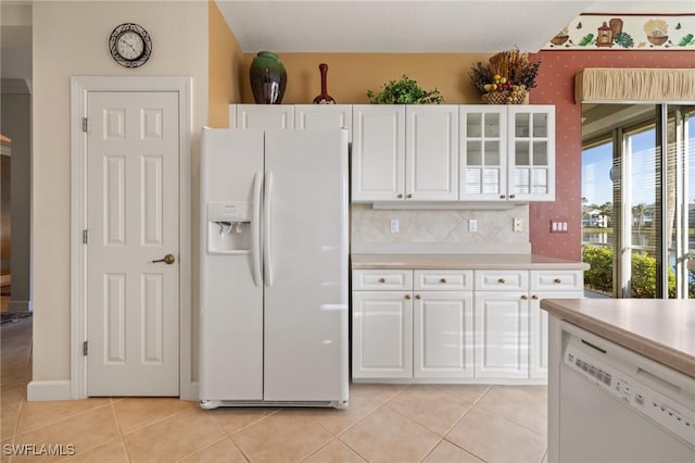 kitchen with decorative backsplash, white appliances, white cabinetry, and light tile patterned flooring