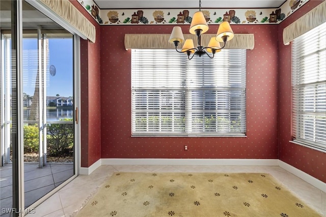 unfurnished dining area with tile patterned flooring, a water view, and a notable chandelier