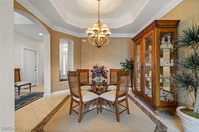 dining room featuring a notable chandelier, light tile patterned flooring, ornamental molding, and a tray ceiling