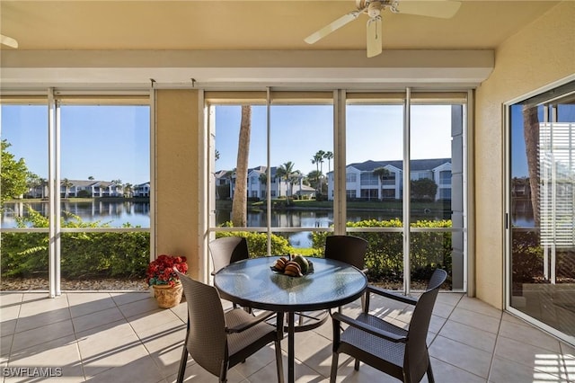 sunroom / solarium with ceiling fan and a water view