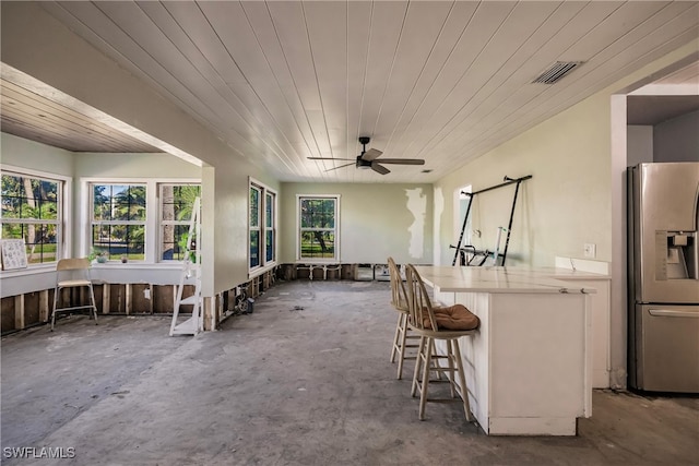 kitchen with a kitchen bar, stainless steel fridge, ceiling fan, and wood ceiling