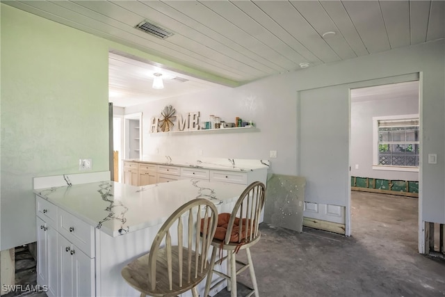 kitchen featuring a kitchen breakfast bar, kitchen peninsula, and white cabinets