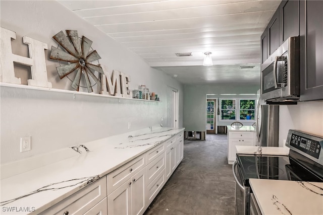 kitchen featuring appliances with stainless steel finishes, white cabinetry, and light stone counters