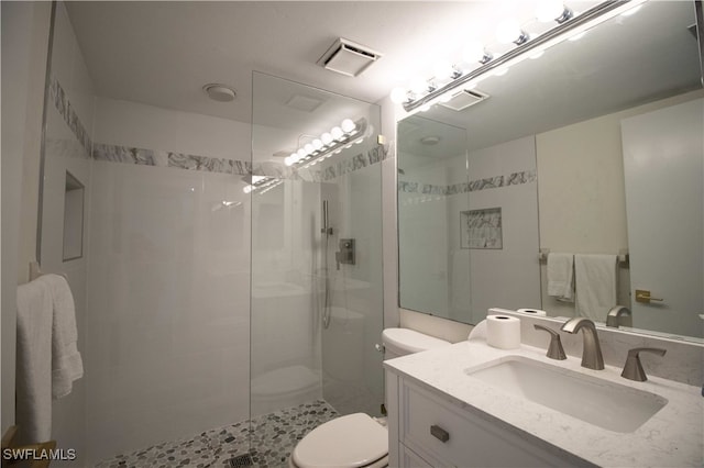 bathroom with toilet, vanity, and tiled shower